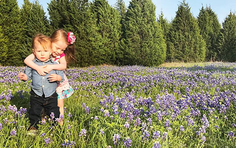 Two young children playing in a field of bluebonnets